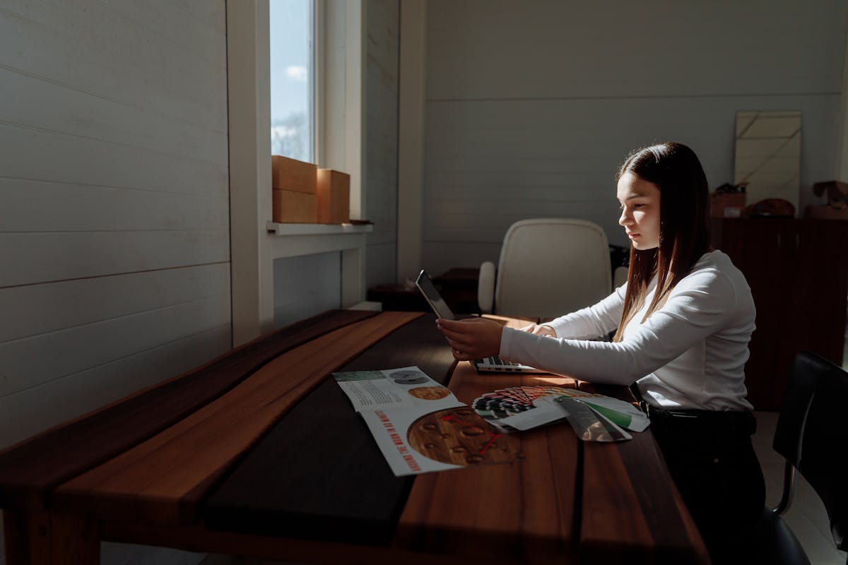 Femme travaillant sur une tablette à un bureau en bois baigné de lumière naturelle